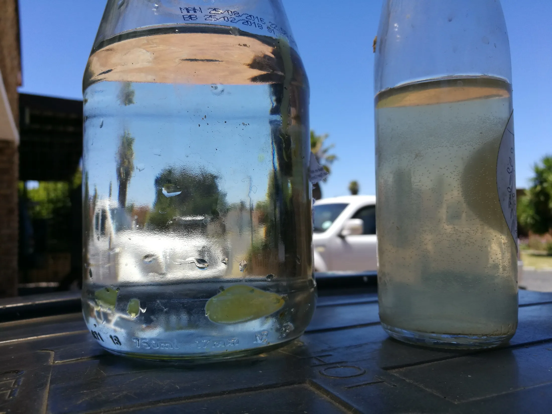 Two water samples standing side by side - one cloudy and discoloured, one clear