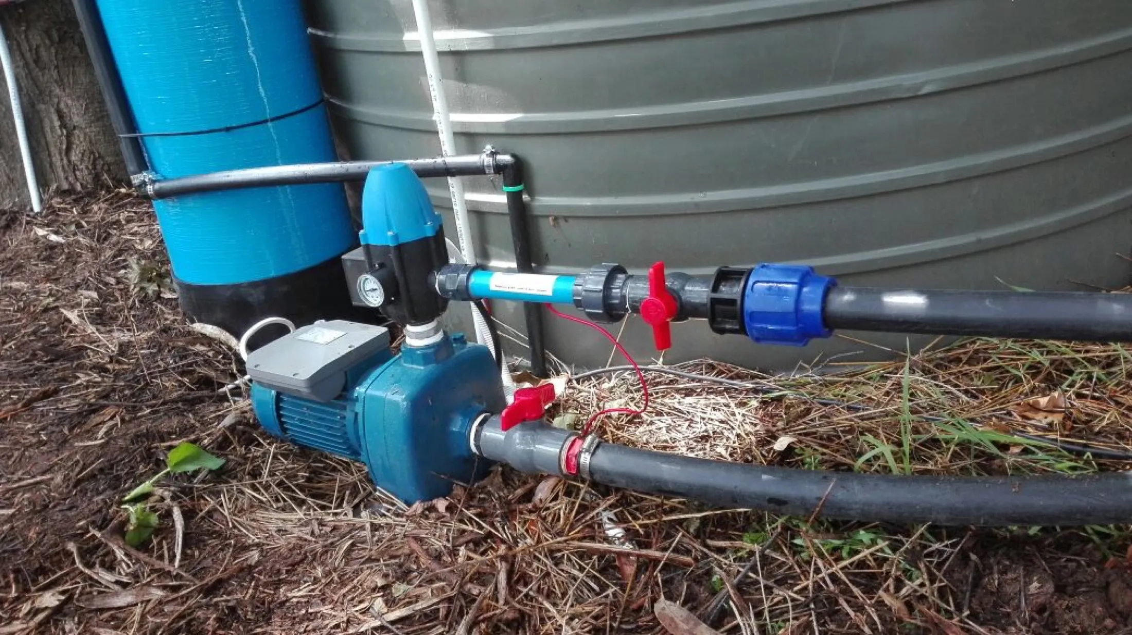 Pump and pipework installed at the base of a large water tank