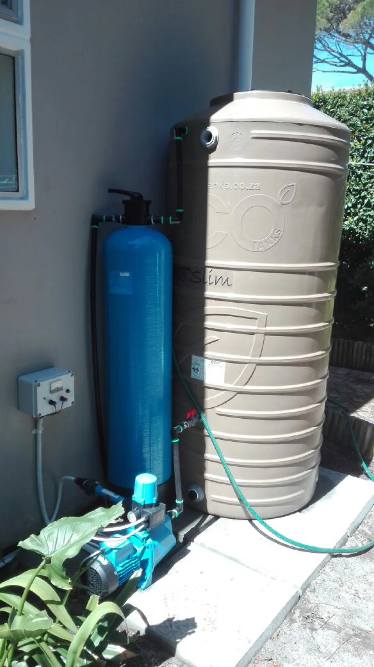 Household water tank and treatment equipment alongside a wall