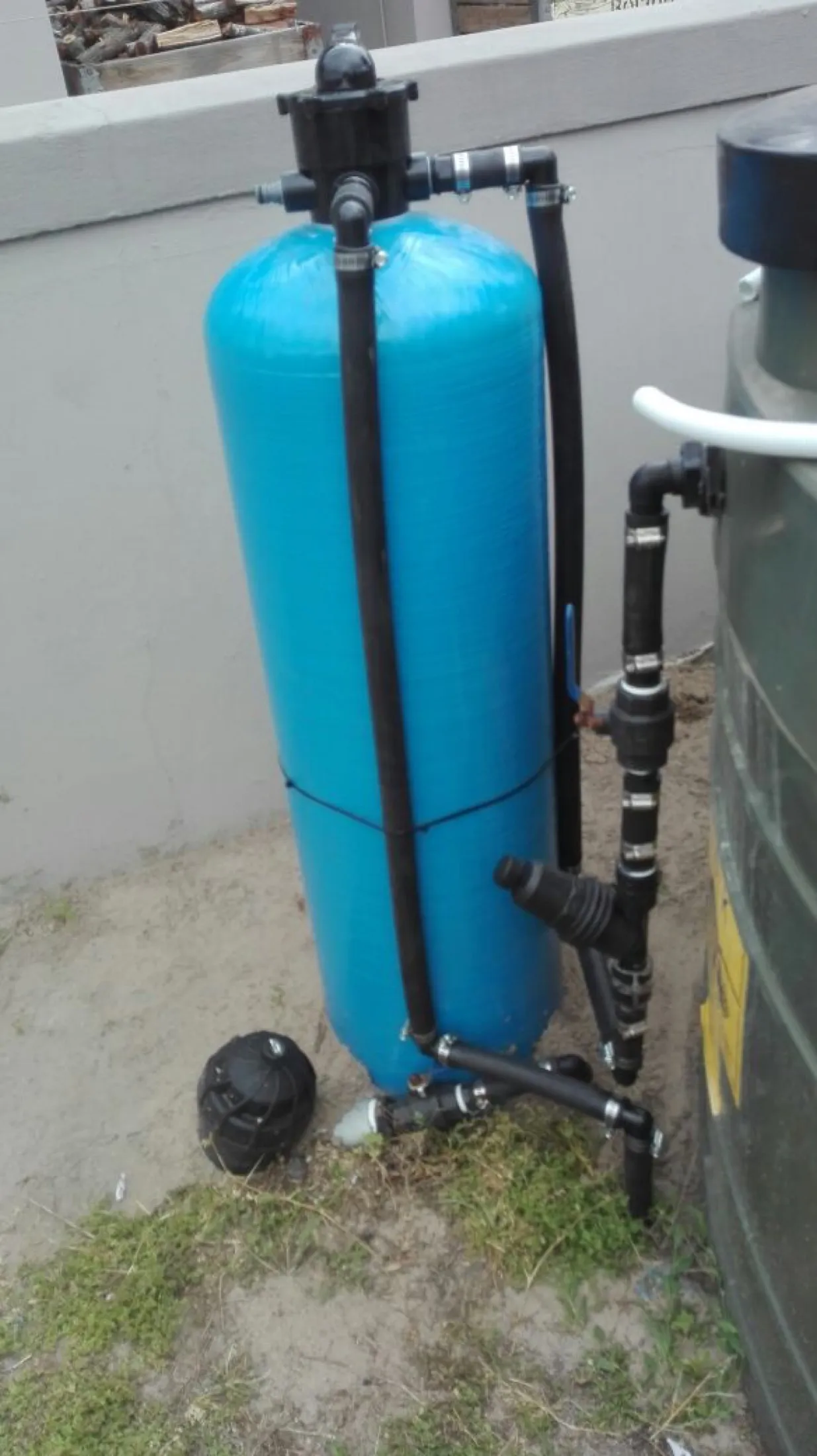 Blue filter vessel installed outdoors on a paved area