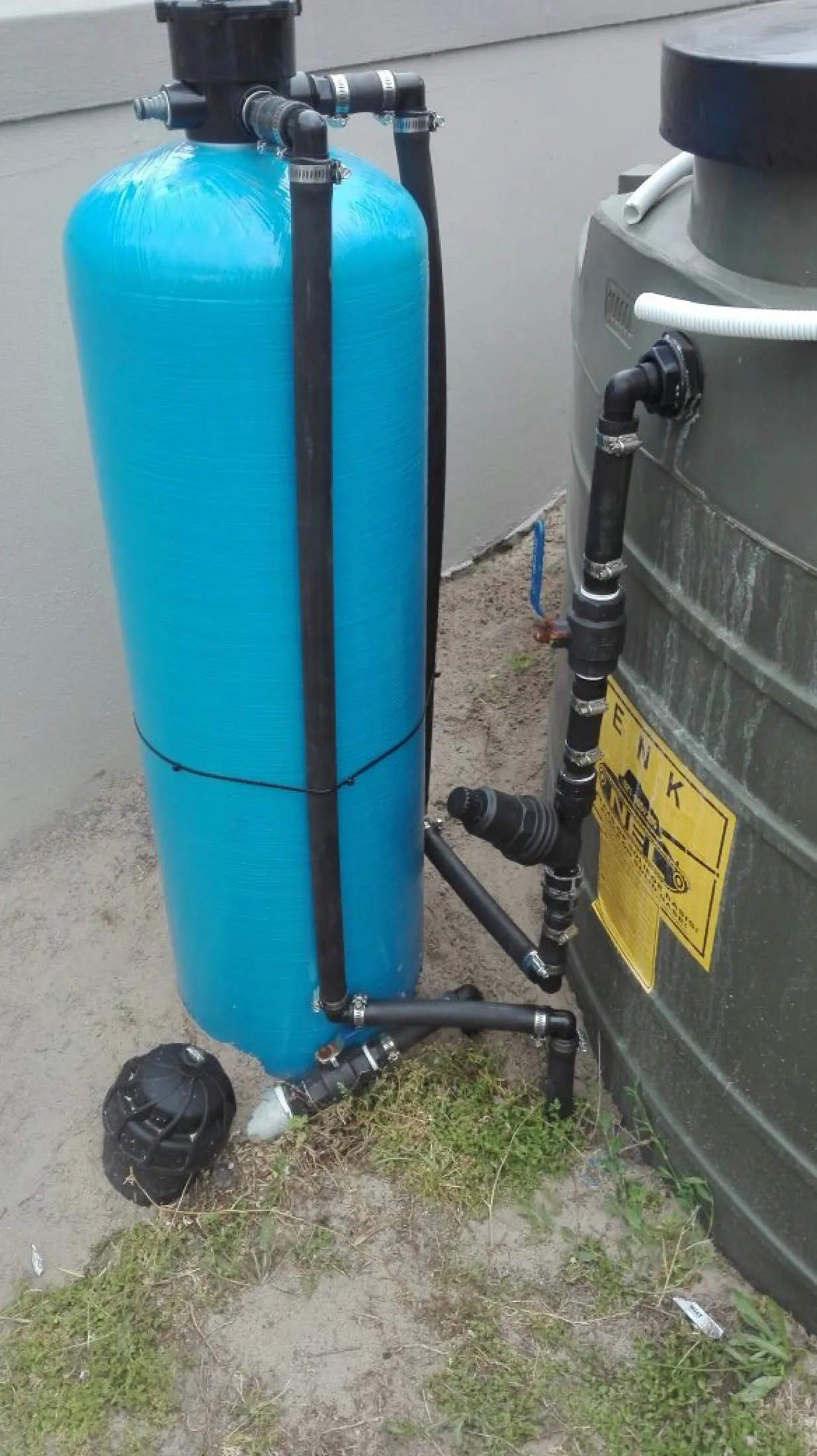 Blue pressure vessel next to a green water tank