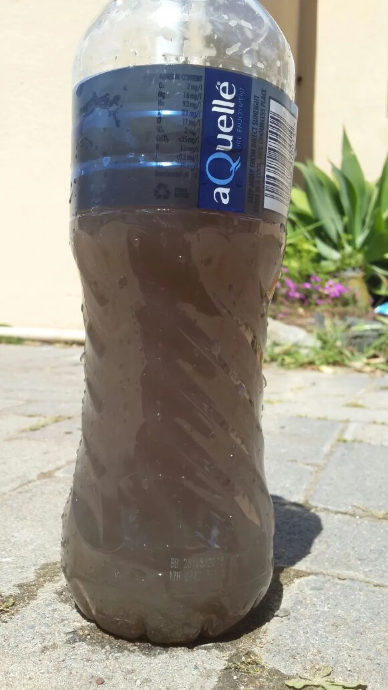 A bottle of heavily discoloured brown borehole water
